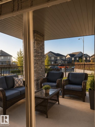 Covered patio featuring a concrete surface, a stacked stone column, and a slatted ceiling - 128 1510 Watt Drive Sw, Edmonton, AB 