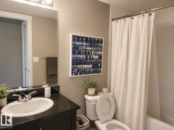 Bathroom featuring a dark vanity with an integrated sink, polished chrome faucet, and a wall-mounted mirror - 