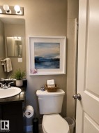 Bathroom featuring a dark wood-finish vanity with an undermount sink, a dark countertop, and a chrome-finish faucet - 