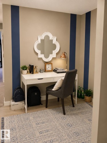Accent wall with vertical navy stripes on neutral beige, wood-finish flooring, and a built-in desk with integrated drawers - 128 1510 Watt Drive Sw, Edmonton, AB 