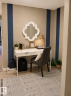 Accent wall with vertical navy stripes on neutral beige, wood-finish flooring, and a built-in desk with integrated drawers - 
