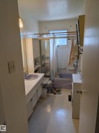 Bathroom featuring a vanity with an integrated sink, built-in shelving, a bathtub with an overhead shower, and window - 