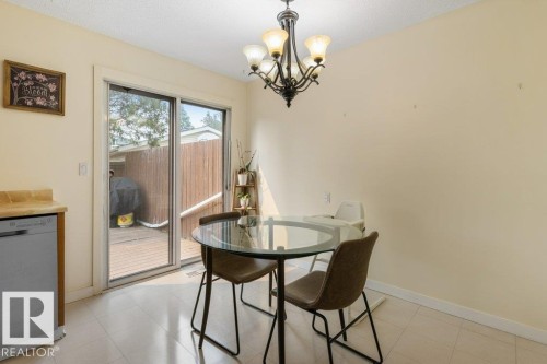 Dining area with neutral wall finishes, tile flooring, and a sliding glass door leading to an outdoor deck - 18609 54 Avenue, Edmonton, AB 