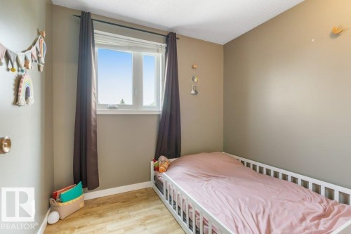 Room featuring a window with a white frame, wood-finish flooring, and light-toned walls - 18609 54 Avenue, Edmonton, AB 