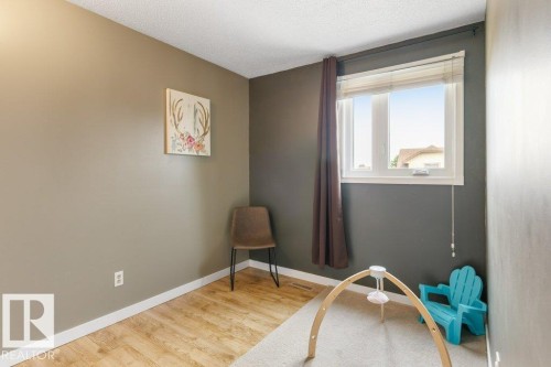 Room featuring wood-finish flooring, a white trim baseboard, and a window with blinds - 18609 54 Avenue, Edmonton, AB 