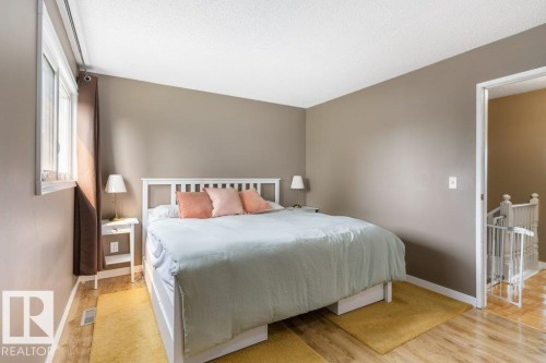 Bedroom featuring wood-finish flooring, neutral wall tones, and a window with white trim - 18609 54 Avenue, Edmonton, AB 