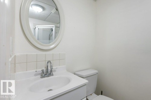 White vanity with an integrated sink, chrome faucet, and tiled backsplash - 18609 54 Avenue, Edmonton, AB 