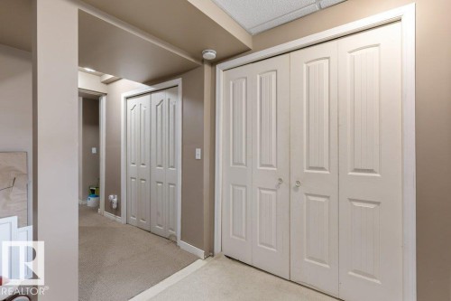 Hallway featuring light beige walls and a neutral carpeted floor - 18609 54 Avenue, Edmonton, AB 