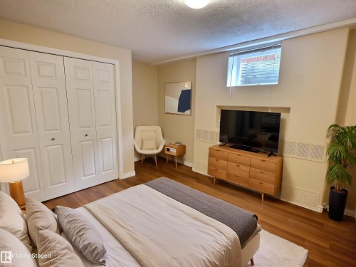 Room featuring wood-finish flooring, bi-fold closet doors, and recessed wall shelving - 79 Grosvenor Boulevard, St. Albert, AB 