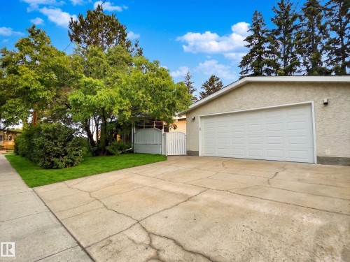 Attached garage with a panel-style door, textured stucco exterior, and exterior lighting fixtures - 79 Grosvenor Boulevard, St. Albert, AB 
