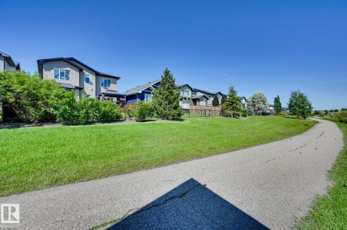Paved pathway bordering expansive green space with mature trees, offering direct access to outdoor recreation - 101 Hilldowns Drive, Spruce Grove, AB 