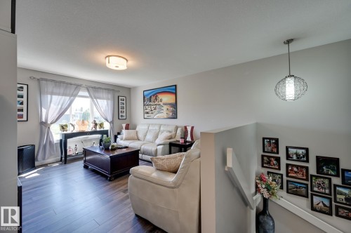 Living space featuring wood-finish flooring, a large window with sheers, and a ceiling-mounted light fixture - 101 Hilldowns Drive, Spruce Grove, AB 