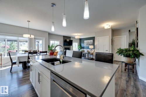 Kitchen island featuring a single-basin sink with a gooseneck faucet, light-toned countertop, and white cabinetry - 101 Hilldowns Drive, Spruce Grove, AB 