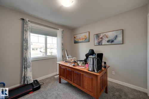 Carpeted interior space featuring neutral wall tones, a large multi-pane window with white trim, and a ceiling-mounted light fixture - 101 Hilldowns Drive, Spruce Grove, AB 