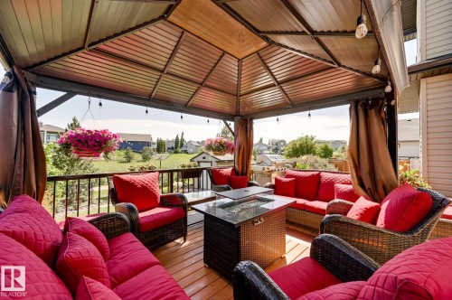 Covered outdoor living space featuring a gazebo structure with a slatted ceiling, string lighting, and privacy curtains - 101 Hilldowns Drive, Spruce Grove, AB 