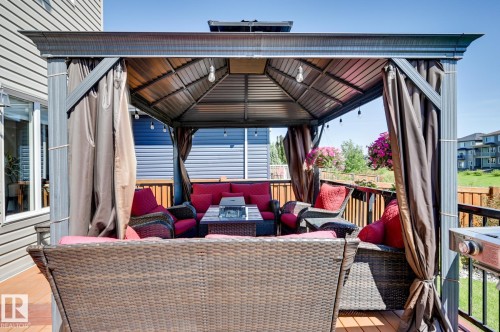 Expansive outdoor deck featuring a fixed gazebo with pull-down privacy curtains, string lighting, and a built-in fire pit table - 101 Hilldowns Drive, Spruce Grove, AB 