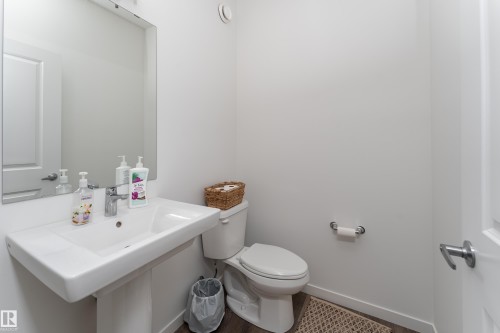 Contemporary powder room featuring a pedestal sink, chrome fixtures, and a wall-mounted mirror - 2522 152 Avenue Nw, Edmonton, AB - Indoor Photo Showing Bathroom