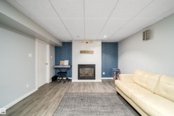 Finished living space featuring a built-in fireplace, wood-finish flooring, drop ceiling, and an accent wall with a geometric pattern - 