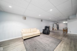 Spacious room featuring wood-finish flooring, light grey walls, white baseboards, and a dropped ceiling with recessed lighting - 