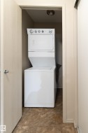 Dedicated laundry closet featuring a white stacked washer and dryer unit - 