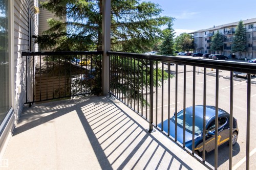 Private balcony featuring a concrete surface, black metal railing, and access via a glass sliding door - #214 1188 Hyndman Rd Nw, Edmonton, AB - Outdoor With Exterior