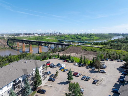 River valley scenery with a prominent bridge structure, multiple parking areas, and mature evergreen landscaping - #214 1188 Hyndman Rd Nw, Edmonton, AB - Outdoor With View
