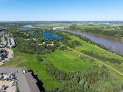 Expansive green spaces featuring a winding river, multiple ponds, mature trees, and natural pathways - 
