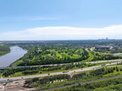 Expansive aerial showcasing a broad river, a multi-lane highway, and a distant city skyline - 