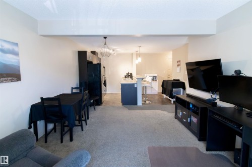 Open-concept living space featuring carpeted flooring, neutral wall tones, and recessed lighting - #214 1188 Hyndman Rd Nw, Edmonton, AB - Indoor Photo Showing Living Room