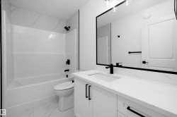 Contemporary bathroom featuring a white vanity with a quartz countertop, an undermount sink, and matte black fixtures - 