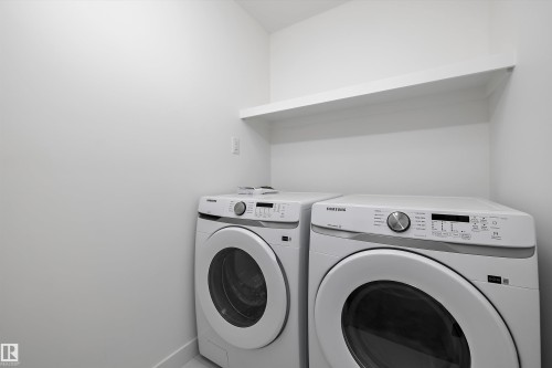 Dedicated laundry space featuring a white floating shelf, light-toned walls, and tile flooring - 915 Elderberry Landing Nw, Edmonton, AB - Indoor Photo Showing Laundry Room