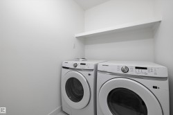 Dedicated laundry space featuring a white floating shelf, light-toned walls, and tile flooring - 