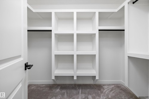 Walk-in closet featuring built-in shelving, hanging rods, and grey carpet flooring - 915 Elderberry Landing Nw, Edmonton, AB - Indoor With Storage