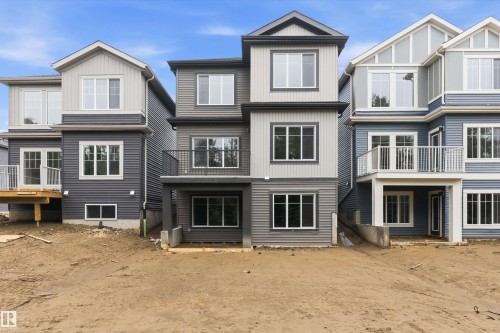 Contemporary multi-level exterior featuring multiple windows, a second-story balcony with metal railing, and a ground-floor patio - 915 Elderberry Landing Nw, Edmonton, AB - Outdoor With Facade
