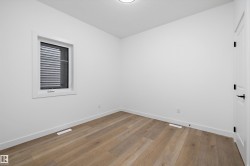 Room featuring light wood-finish flooring, white baseboards, and a white ceiling - 