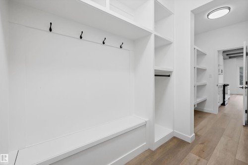 Built-in mudroom storage featuring a white bench, black coat hooks, and open shelving - 915 Elderberry Landing Nw, Edmonton, AB - Indoor With Storage