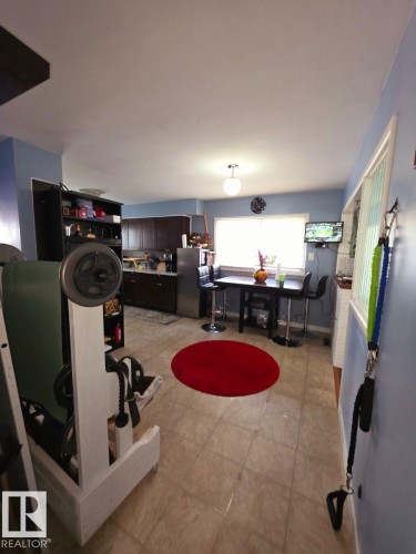 Kitchen area featuring tile flooring, dark wood cabinetry, a stainless steel refrigerator, and a window above the sink - 10404 116 Avenue, Edmonton, AB 
