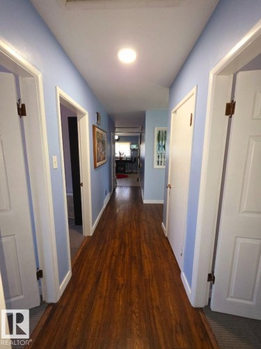 Hallway featuring wood-finish flooring, light blue wall paint, white trim, and recessed lighting - 10404 116 Avenue, Edmonton, AB 