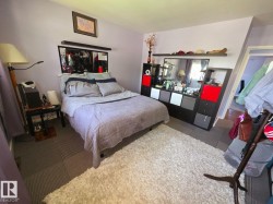 Bedroom featuring light-toned wall paint and patterned carpet tiles - 