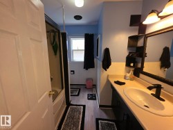 Contemporary bathroom featuring a single vanity with an integrated sink, black faucet, and overhead bar lighting - 