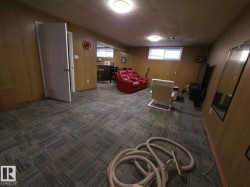 Spacious room featuring wood-finish wall paneling, patterned carpet tile flooring, and overhead flush-mount lighting - 