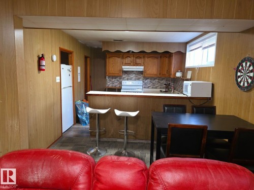 Kitchenette with wood-finish paneling, wood cabinetry, and a patterned tile backsplash - 10404 116 Avenue, Edmonton, AB 