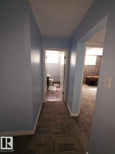 Hallway with patterned carpet flooring, light blue walls, and white baseboards - 10404 116 Avenue, Edmonton, AB 