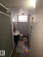 Bathroom featuring a glass-enclosed shower, a vanity with a white basin sink, wood-finish flooring, and a window with horizontal blinds - 