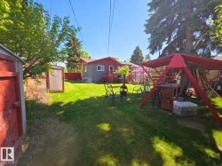Expansive green lawn with a red-painted shed and a framed greenhouse structure - 