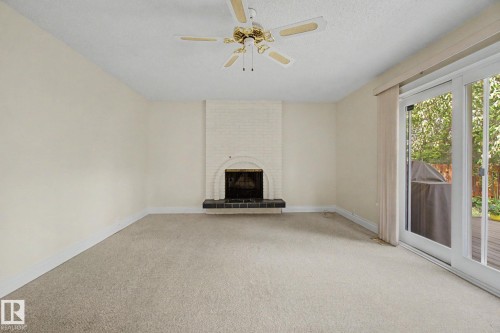 Living area featuring a painted brick fireplace with a dark hearth, ceiling fan, and carpeted flooring - 170 Westridge Rd, Edmonton, AB - Indoor With Fireplace