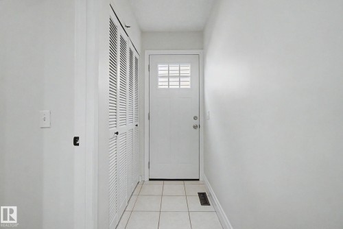 Entryway featuring a paneled door with grid window insert, louvered bi-fold doors, white ceramic tile flooring, and white painted walls - 170 Westridge Rd, Edmonton, AB - Indoor Photo Showing Other Room