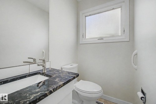 Bathroom vanity with a dark patterned countertop, integrated sink, and brushed nickel faucet - 170 Westridge Rd, Edmonton, AB - Indoor Photo Showing Bathroom