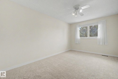 Carpeted room featuring a white ceiling fan with integrated lighting, a window with exterior tree foliage, and light-colored walls with white baseboards - 170 Westridge Rd, Edmonton, AB - Indoor Photo Showing Other Room