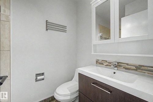 Bathroom vanity featuring a white integrated sink, chrome faucet, and wood-finish cabinetry - 170 Westridge Rd, Edmonton, AB - Indoor Photo Showing Bathroom